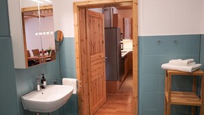 A bathroom with a sink, mirror, wooden door, and a towel rack. - Ferienwohnung Krabbe (Kopendorf auf Fehmarn)