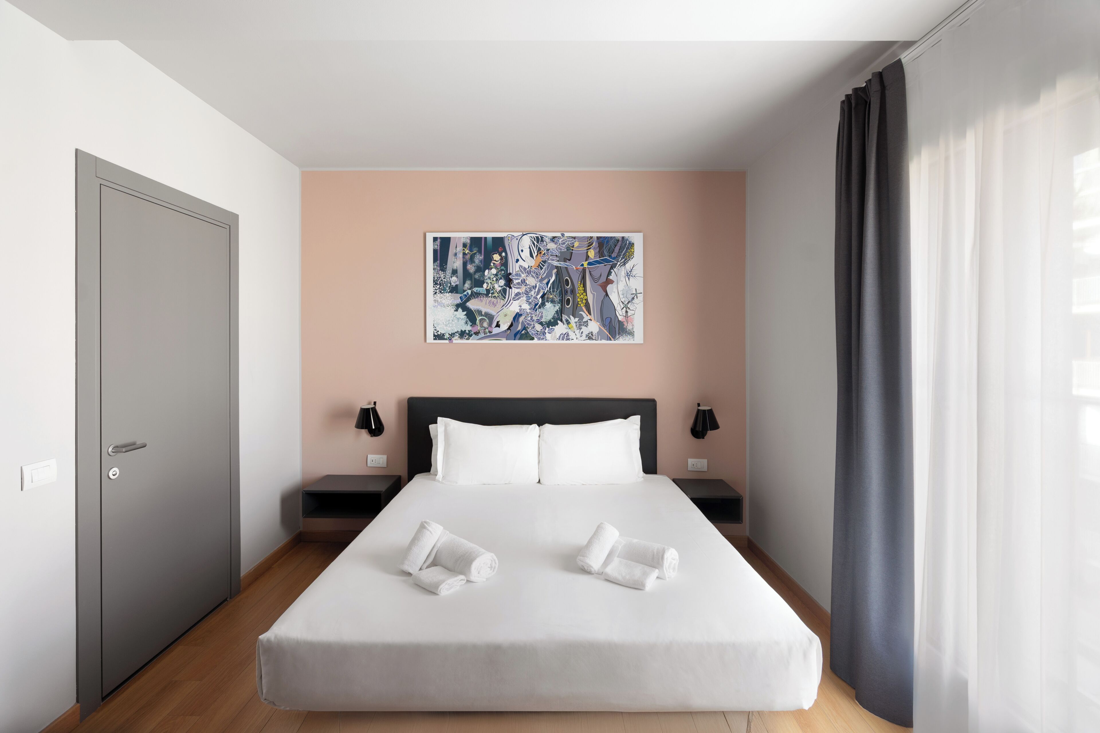 Une chambre d’hôtel moderne avec un grand lit, un tableau au mur et une vue sur la ville.