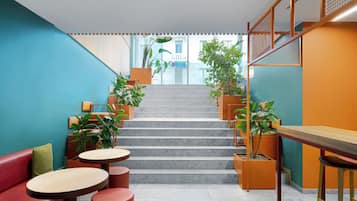 A modern interior with a staircase, seating areas, and potted plants.
