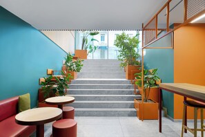 A modern interior with a staircase, seating areas, and potted plants. - 21 House of Stories Città Studi (Milan)