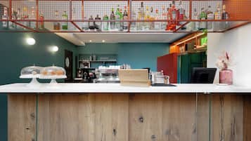 Een bar met een houten toonbank, flessenkasten en een neonbord.