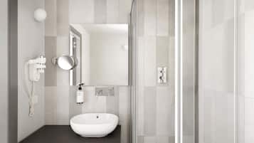 A modern bathroom with a white sink, a handheld mirror, a handheld showerhead, and a glass shower enclosure.