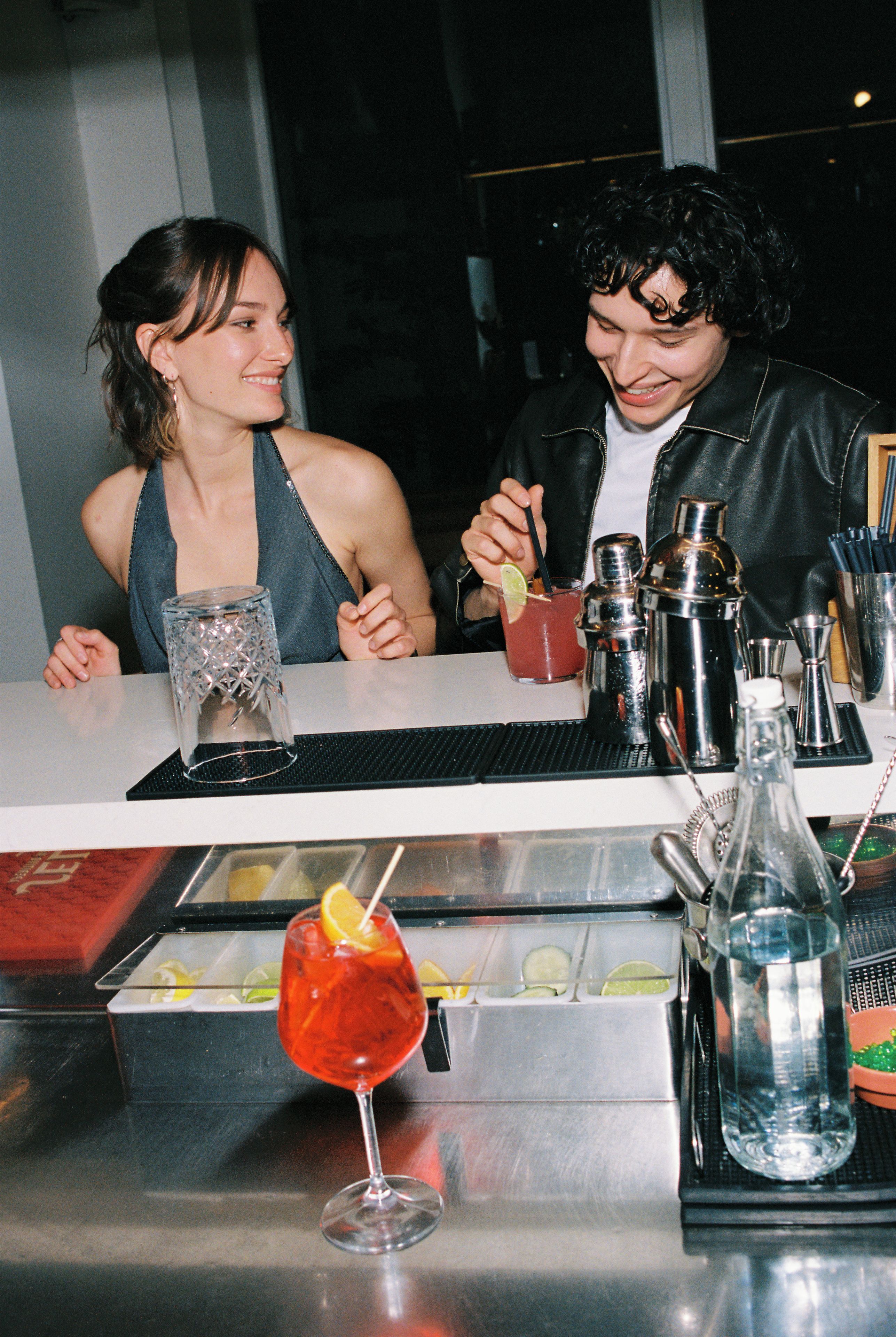Un bar con cócteles, una botella y utensilios de bar.