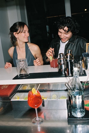Une scène de bar avec un cocktail, une bouteille et des ustensiles de bar.