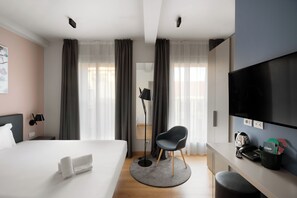 A modern hotel room with a bed, a desk with a computer, a chair, a TV, and a lamp. - 21 House of Stories Città Studi (Milan)