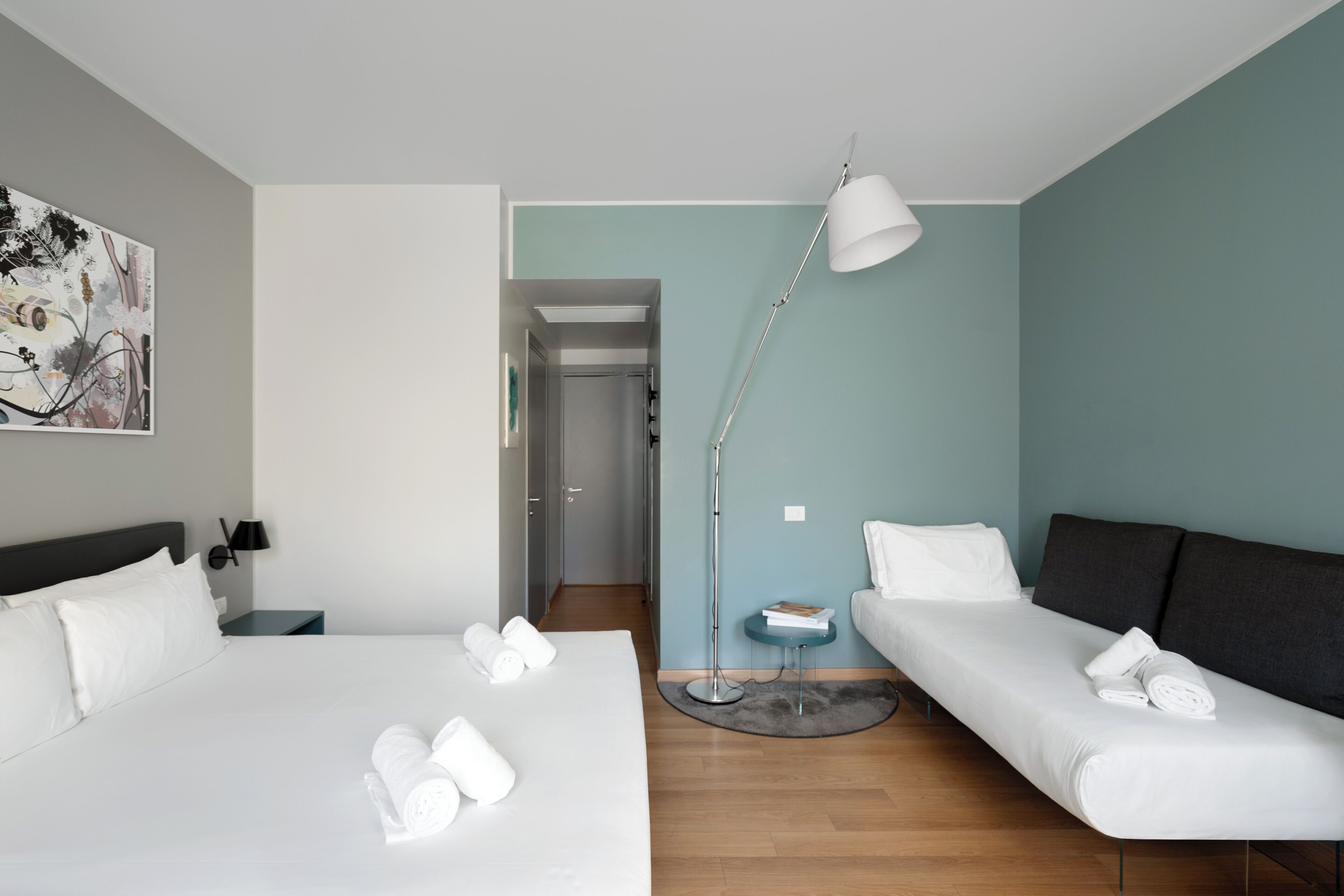 Habitación de hotel con dos camas, un escritorio, una lámpara y un cuadro en la pared.