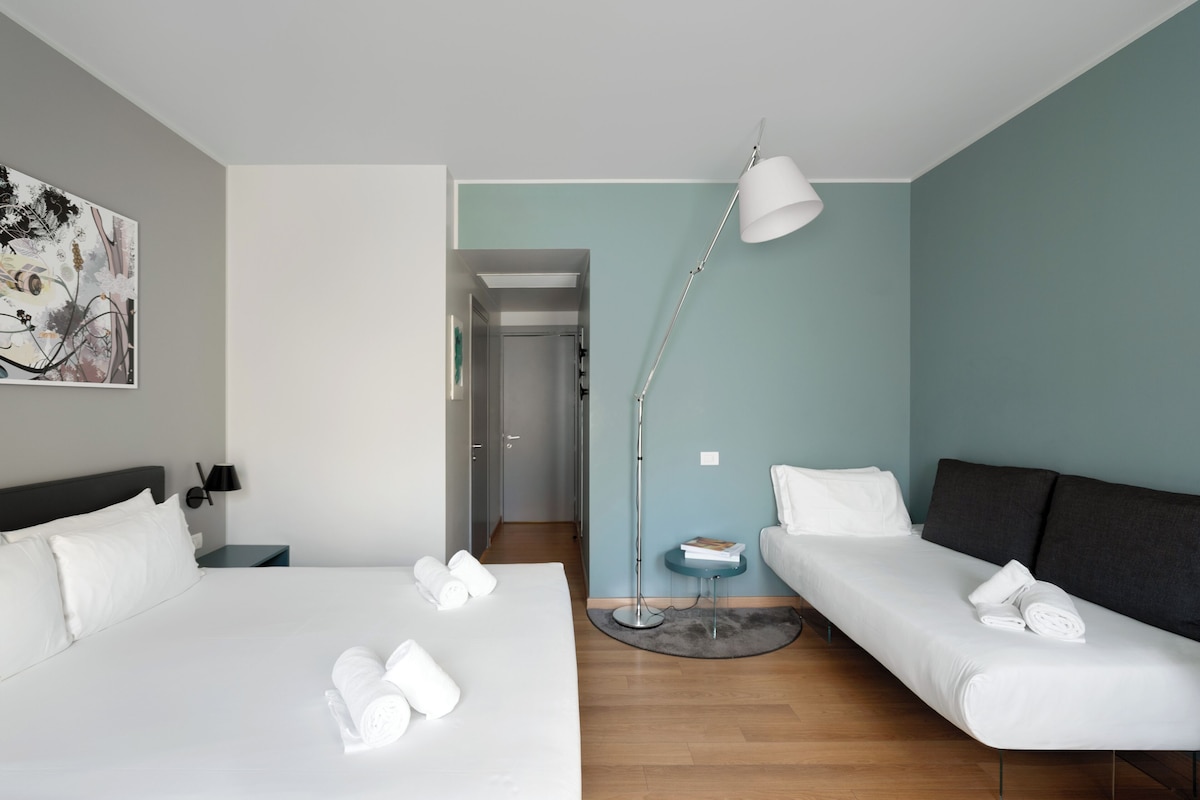 Habitación de hotel con dos camas, un escritorio, una lámpara y un cuadro en la pared.
