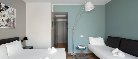 Habitación de hotel con dos camas, un escritorio, una lámpara y un cuadro en la pared.