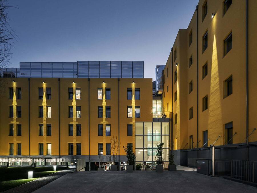 A multi-story building with a yellow facade, large windows, and a flat roof.