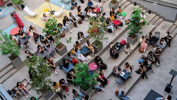An outdoor seating area with tables and chairs, surrounded by greenery and potted plants.