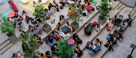 An outdoor seating area with tables and chairs, surrounded by greenery and potted plants.