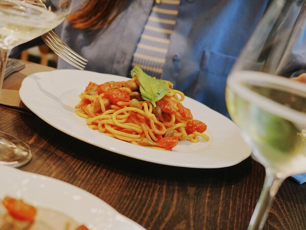 A plate of spaghetti with tomato sauce and a basil leaf on a white plate.