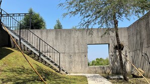 Ein Betongebäude mit einer Treppe, einem kleinen Fenster und einem Baum.