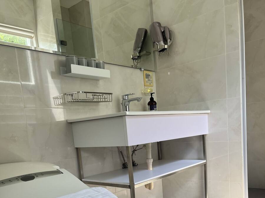 A modern bathroom with a white toilet, a white sink with a mirror above, and a towel on the toilet.