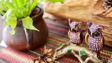 Ambiente rústico com uma planta em vaso, duas figuras de coruja e um ramo de madeira.