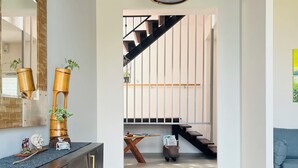 Ein modernes Interieur mit Treppe, einem Holzkonsole und einer Pendelleuchte.