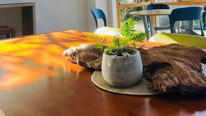 Ein Zimmer mit Holztisch, einem Topfpflanzen und einem großen Fenster mit Blick auf Grünfläche.