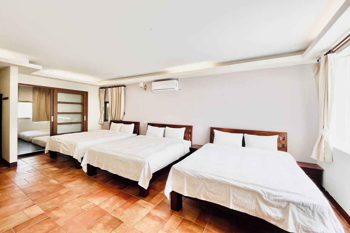 Habitación de hotel con tres camas, armario corredero y equipo de aire acondicionado.