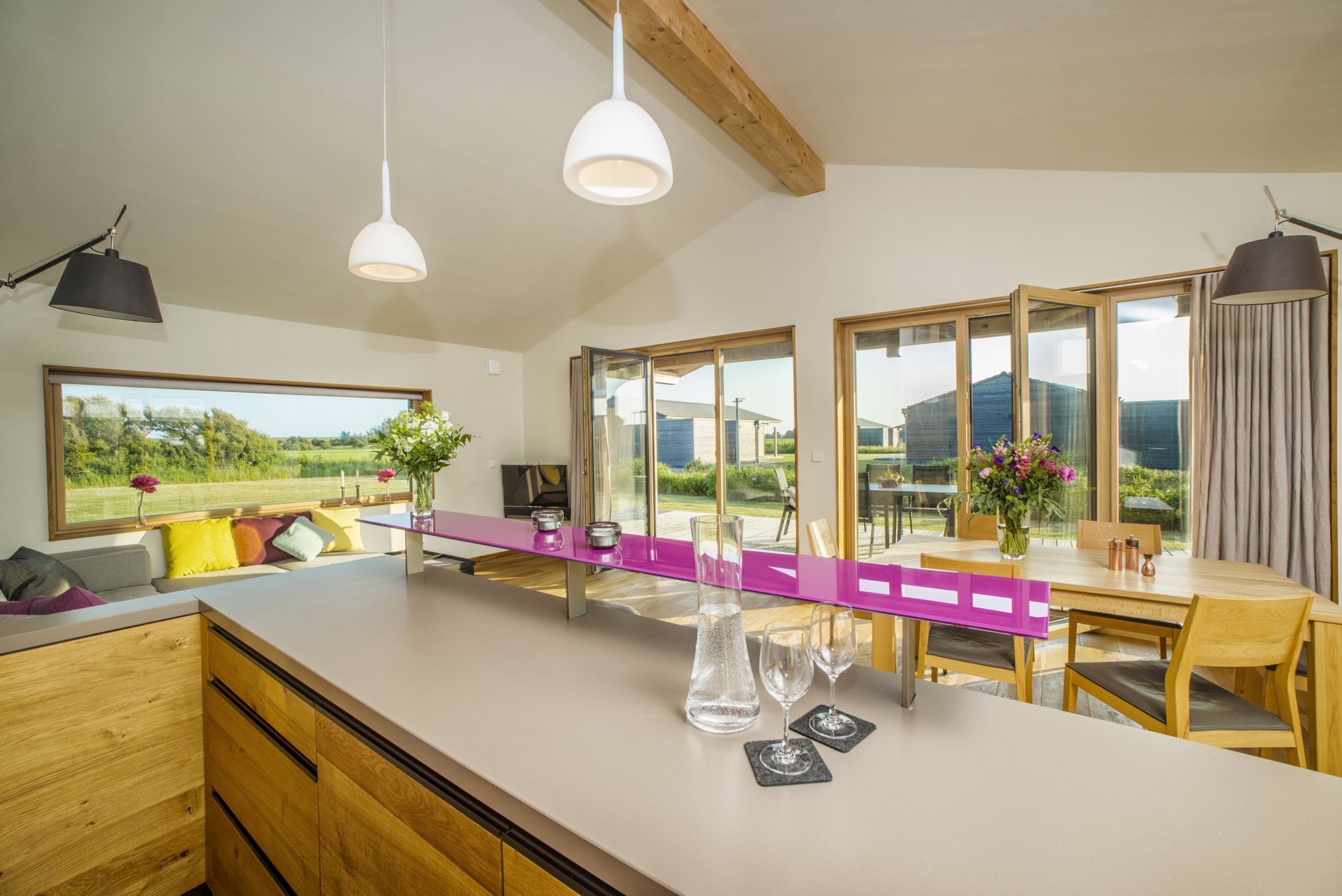Een moderne keuken met een groot eiland, houten kastjes en uitzicht op de omgeving.