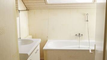 A small, basic bathroom with a skylight, a sink, and a bathtub.