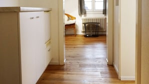 A narrow hallway with wooden flooring leading to a room with a sloped ceiling and a window. - Adventure Guesthouse (Unterseen)