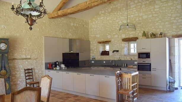 A spacious kitchen with a large island, white cabinetry, and a stone wall backdrop. - Pretty dovecote in the countryside (monestier)