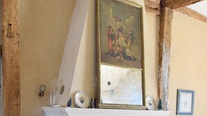 A fireplace with a painting above it, a wooden chair to the left, and a blue chair to the right. - Pretty dovecote in the countryside (monestier)