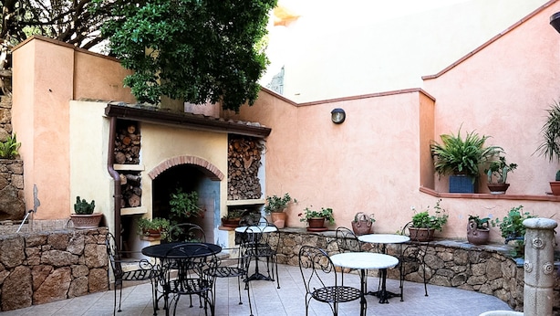 Un patio al aire libre con paredes de piedra, una chimenea y varias mesas y sillas.