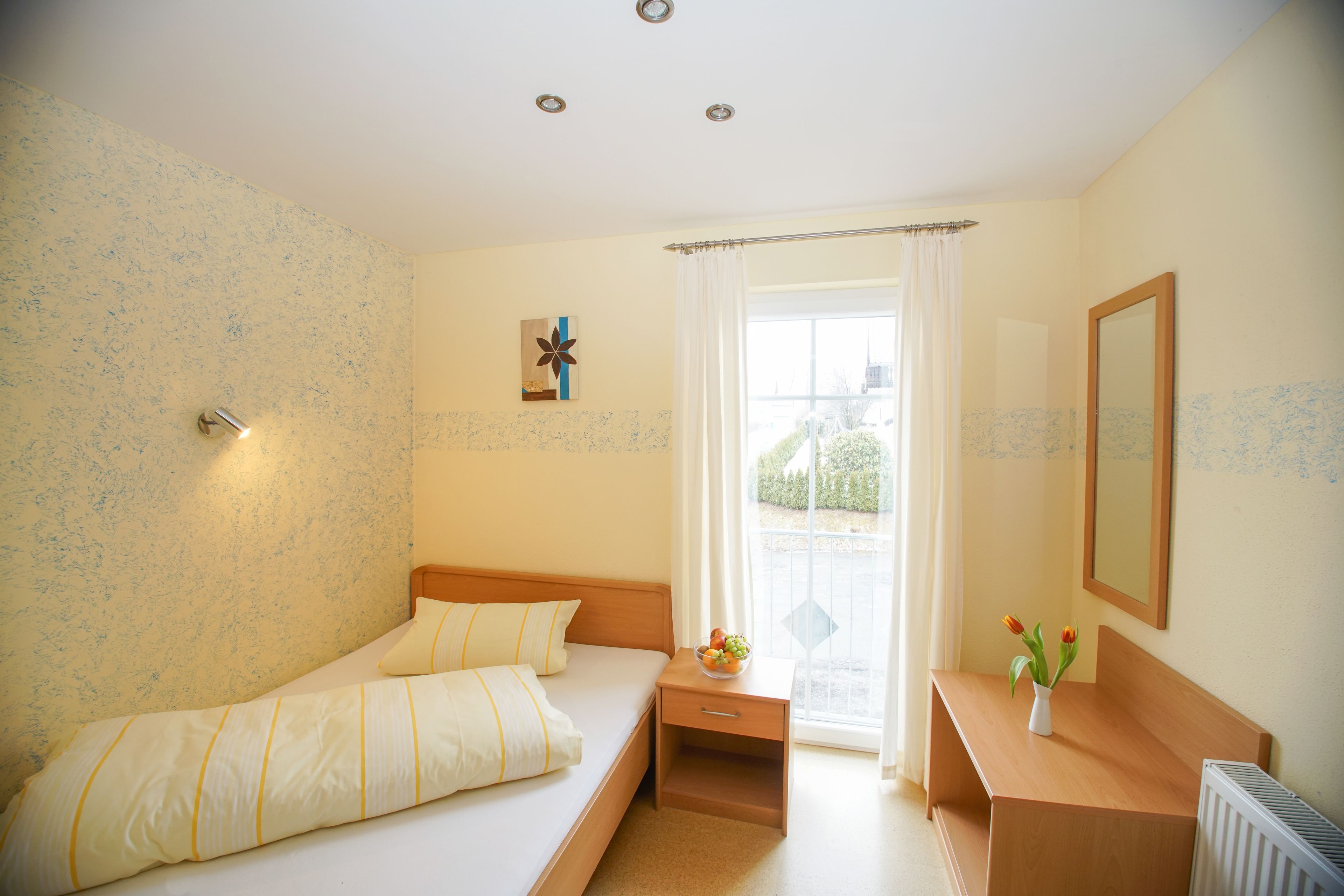 Ein Schlafzimmer mit Bett, Nachttisch und einem Fenster mit Vorhängen.