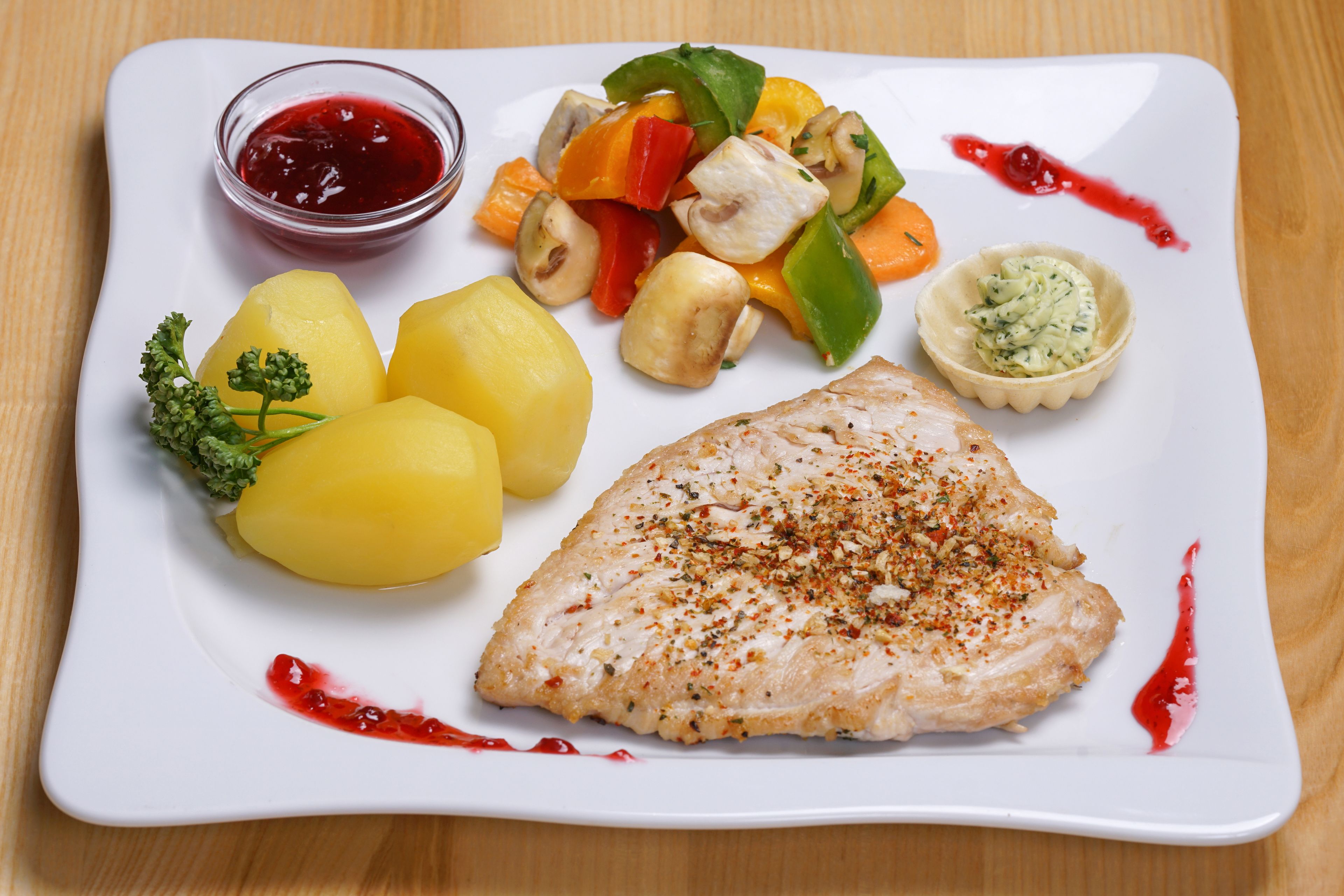 A white plate with a piece of fish, potatoes, and a mix of vegetables.