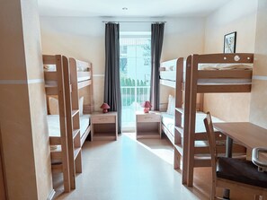 Ein Zimmer mit Etagenbetten, einem Schreibtisch und einem Stuhl.
