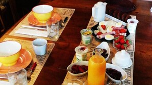 A breakfast setup with bread, fruits, and beverages on a wooden table.