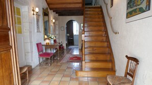 A staircase leading to a second floor, a dining area with a table and chairs, and a wooden chair near the staircase.