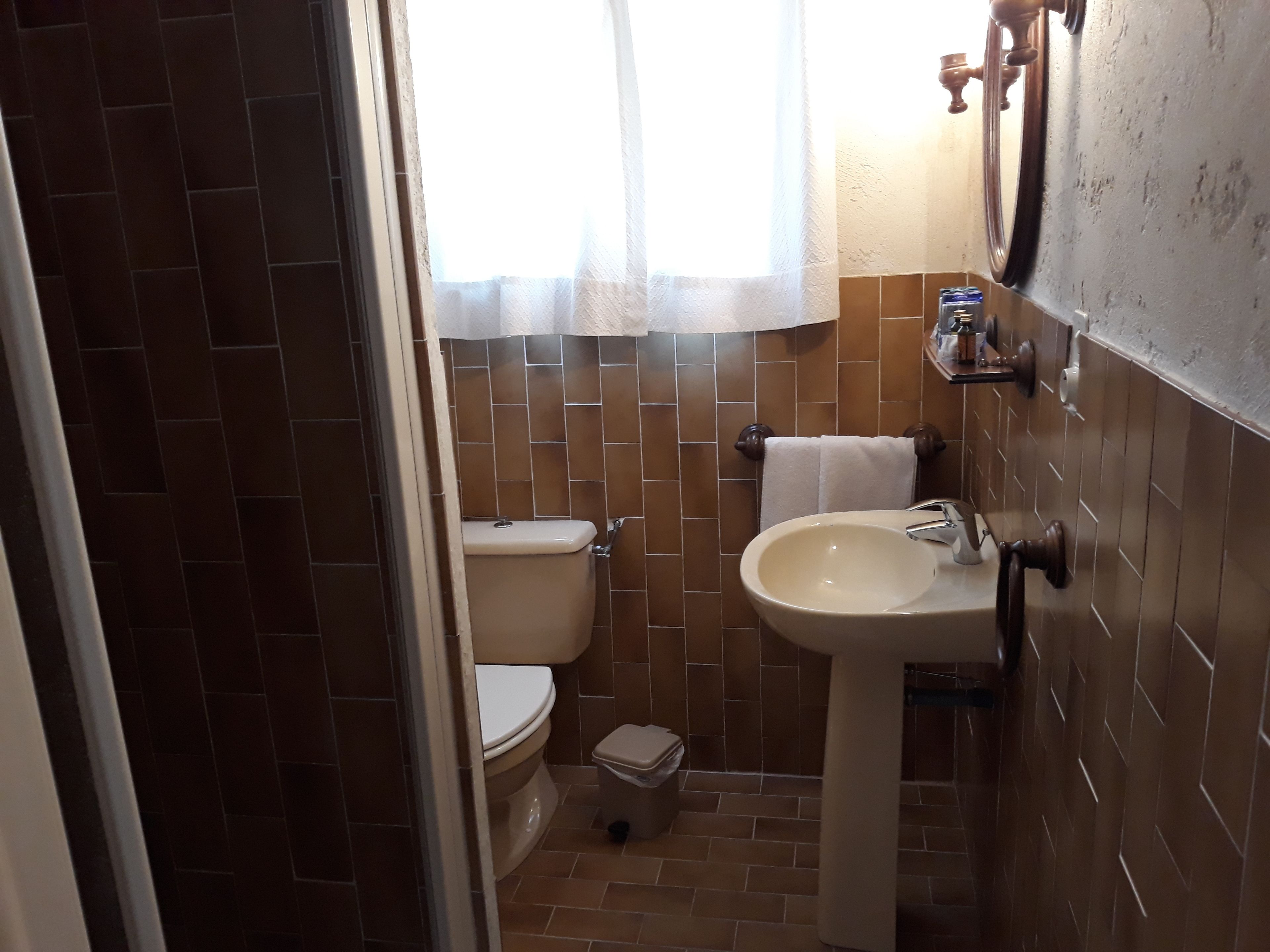A bathroom with a toilet, sink, and a small trash bin.