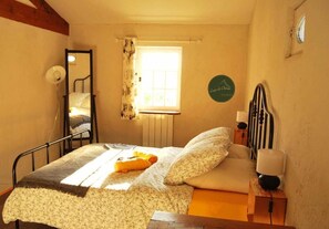 A bedroom with a bed, a window with curtains, a bedside lamp, and a wall clock. - Logis de Chenac (Chenac-Saint-Seurin-d'Uzet)