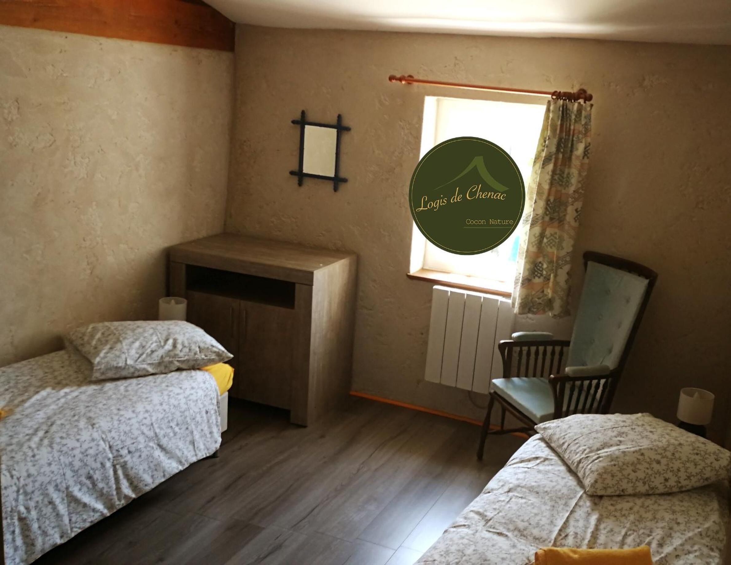 Un dormitorio con dos camas, un escritorio de madera, una silla y una ventana con cortinas.
