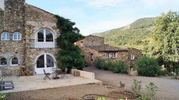 A stone building with arched windows and a patio area with outdoor seating. - Hameau des Claudins (Plan-de-la-Tour)