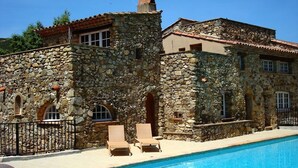 A stone building with a swimming pool, two lounge chairs, and a stone fence. - Hameau des Claudins (Plan-de-la-Tour)