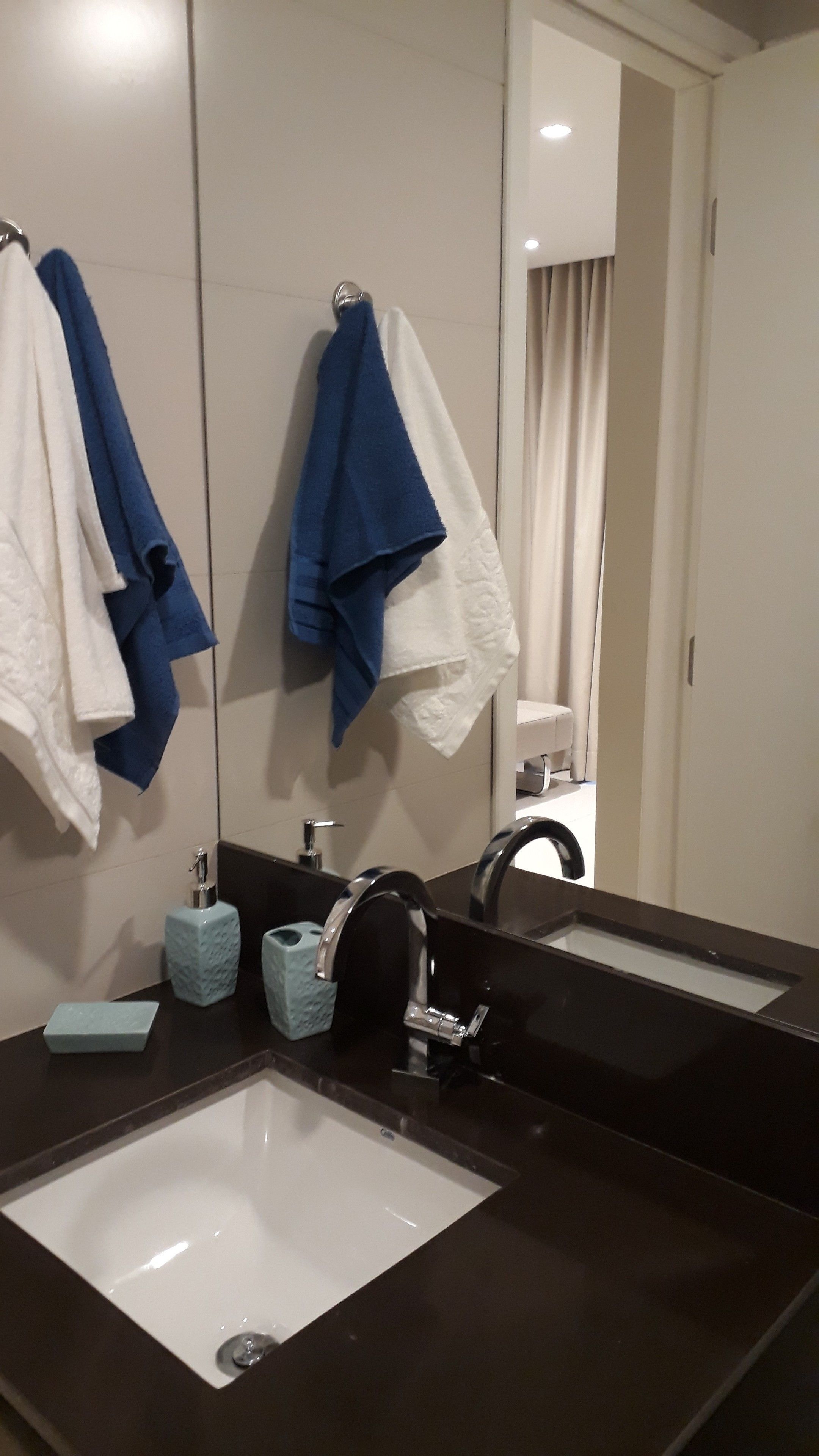 Un bagno con uno specchio grande, due asciugamani appesi, un lavandino e un water visibile nel riflesso.