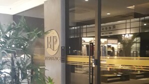 A modern building with a glass facade, a sign reading "HP Residence," and a wooden planter with green plants. - Holanda's Prime - Praia de Tambaú (João Pessoa)