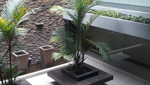A modern indoor space with a brick wall, potted plants, and a large window. - Holanda's Prime - Praia de Tambaú (João Pessoa)