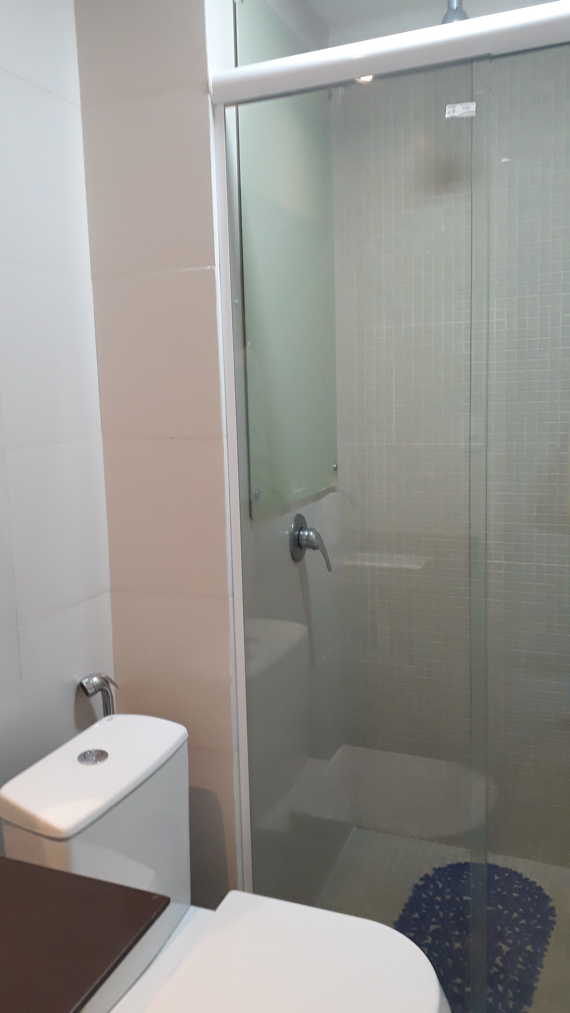 A bathroom with a glass-enclosed shower, a toilet, and a sink.