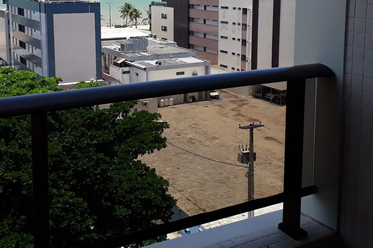 A balcony with a view of a coastal area, including buildings and a sandy beach.