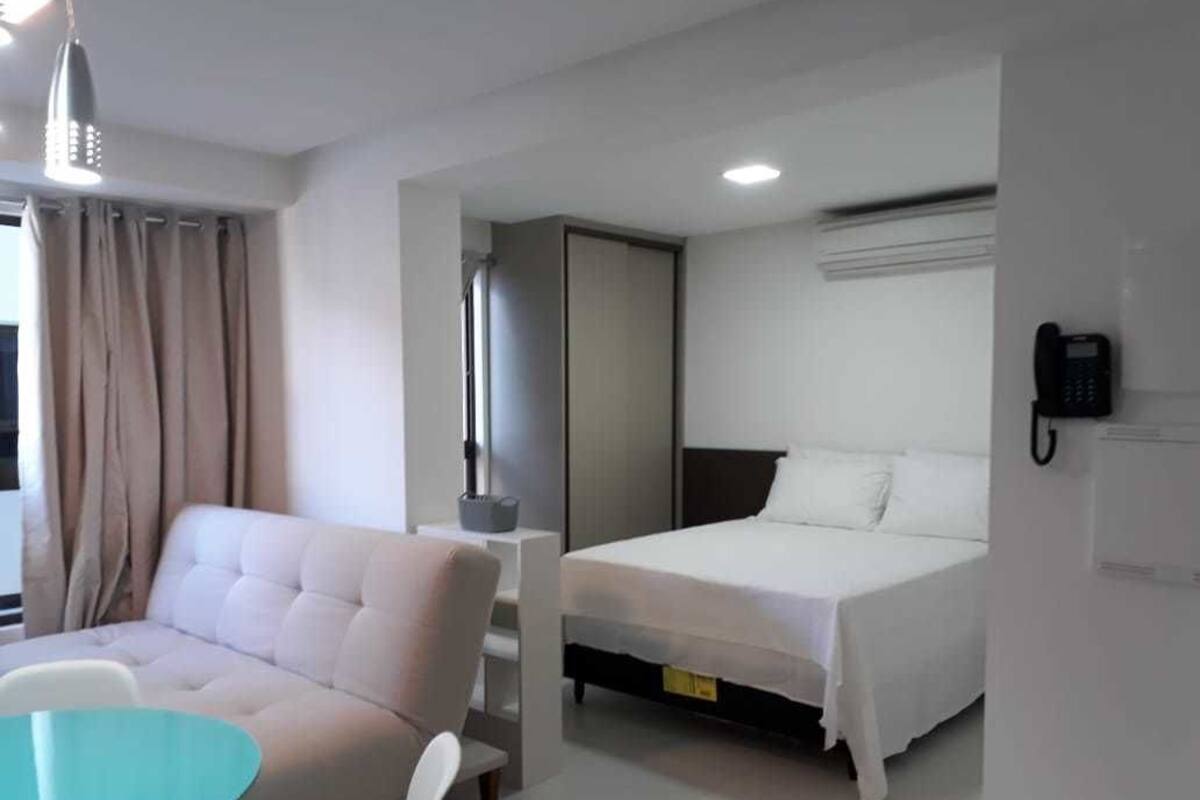 A hotel room with a bed, a sofa, a table, and a phone on the wall.
