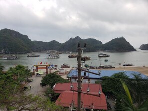 A coastal area with boats docked, a beach, and a building with a red roof. - Cat Ba Plaza Hotel (Hai Phong)