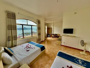 A hotel room with two beds, a TV, a desk, and a view of the sea. - Cat Ba Plaza Hotel (Hai Phong)