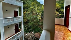 A multi-story building with balconies overlooking a lush green hillside.