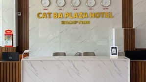 A hotel reception desk with clocks displaying times from London, Paris, Ha Noi, and Tokyo.