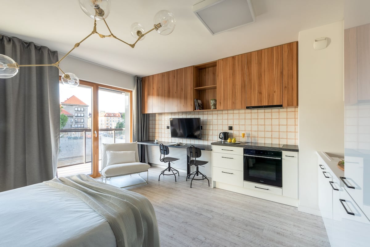 Une cuisine moderne avec des meubles en bois, un four encastré et une grande fenêtre.