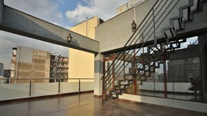 A spacious rooftop terrace with a modern staircase and large windows offering views of the cityscape. - Hotel Wine Palace (Tbilisi)